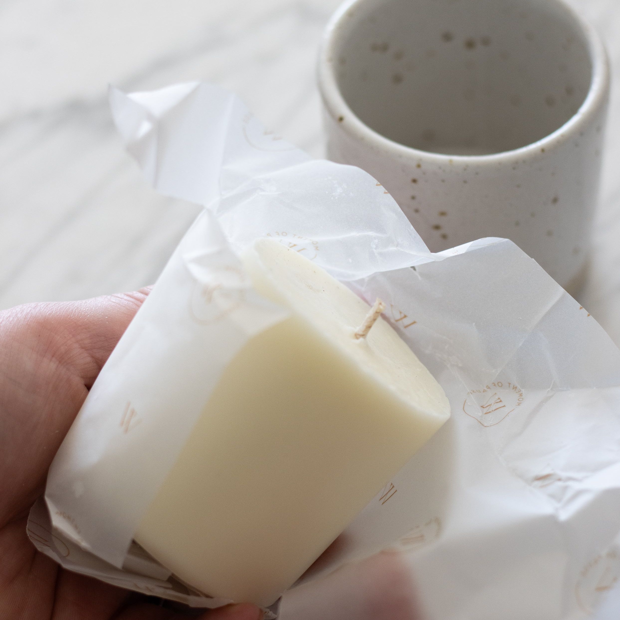 A candle refill is being unwrapped to be placed in a refillable candle