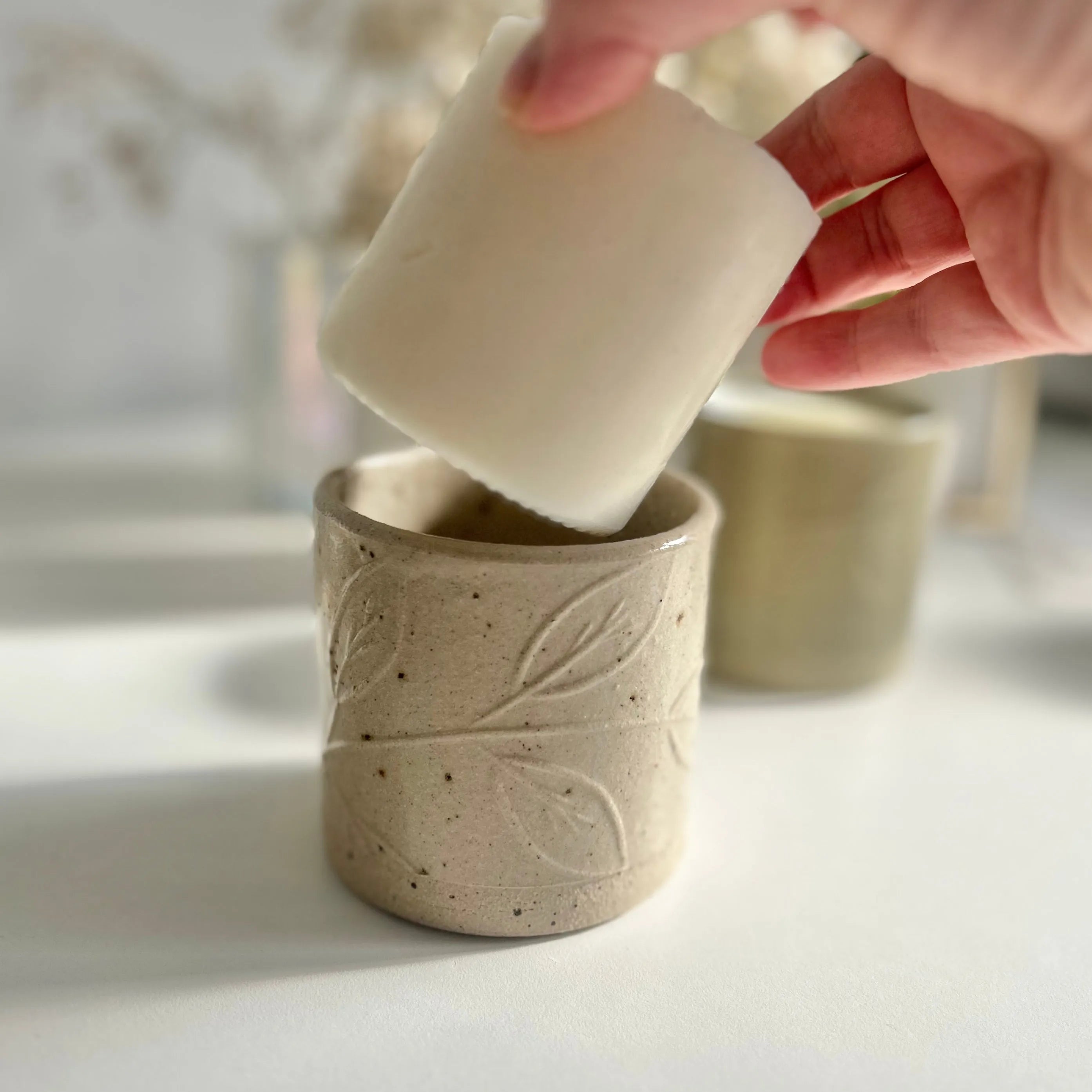 A candle refill is being lowered into a refillable candle