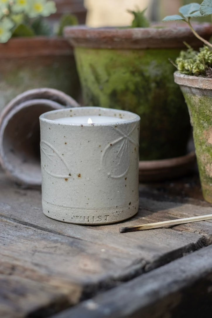 A lit refillable candle in white sits on a worktop