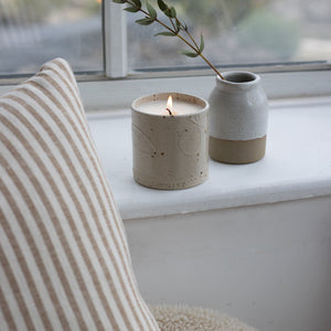 A refillable candle in a nude colour has been placed on a white windowsill