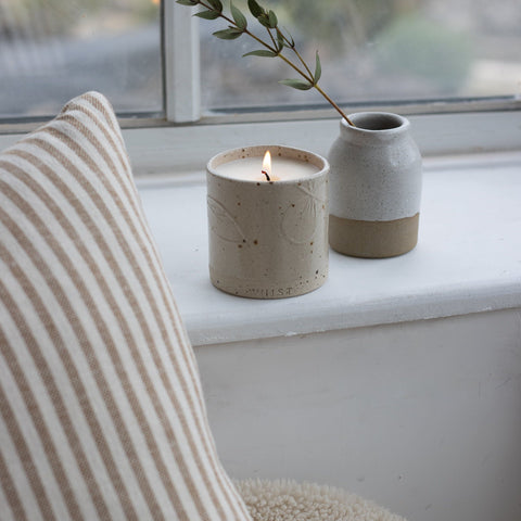 A refillable candle in a nude colour has been placed on a white windowsill