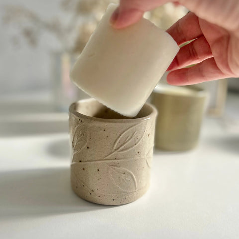 A candle refill is being lowered into a refillable candle