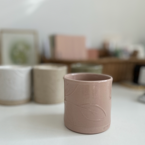 a refillable candle in the colour vintage rose is on a work surface